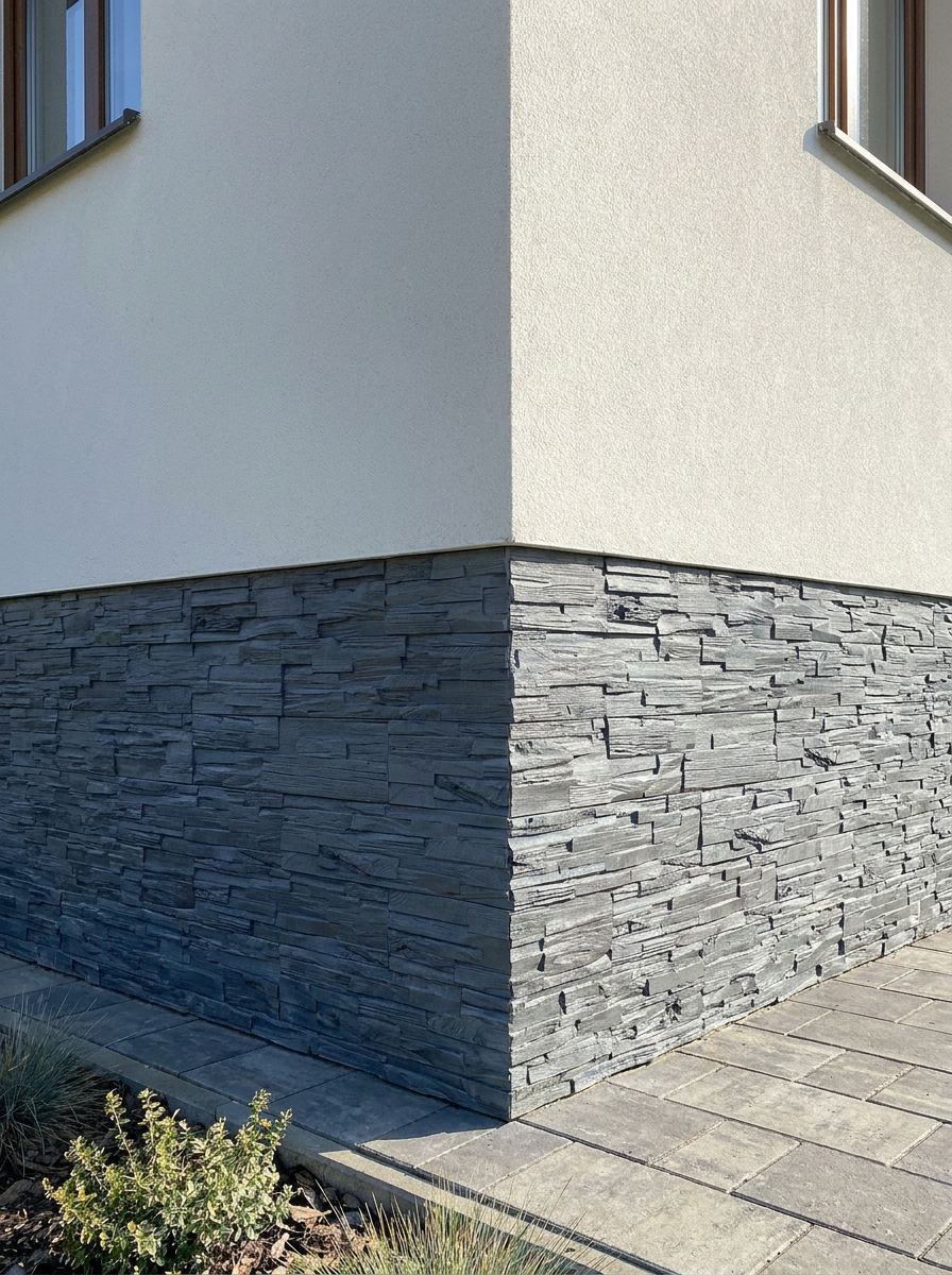 Soclul unei case placat cu piatră decorativă gri închis, la colțul clădirii